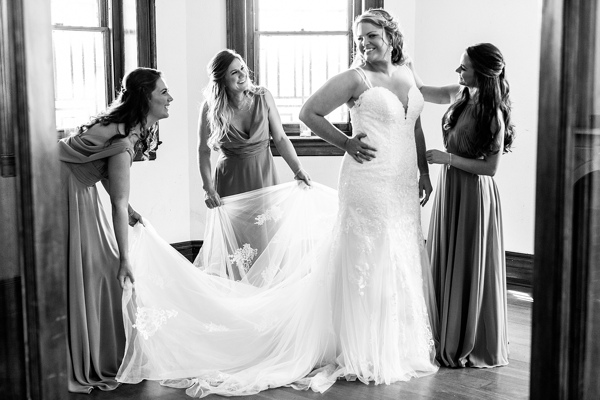 bride gets into gown with bridesmaids photographed by Alexandra Mandato Photography