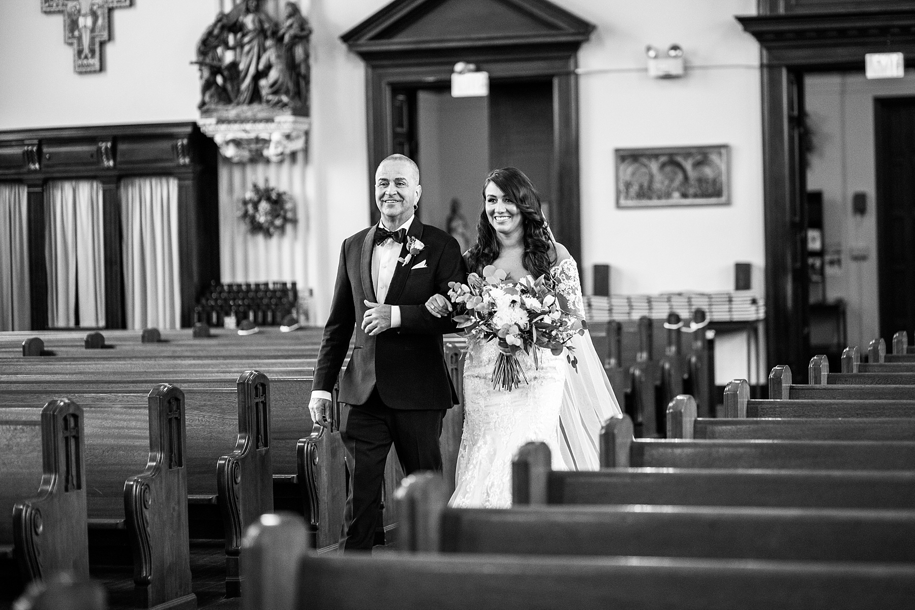 bride walks down aisle in Catholic Church photographed by Alexandra Mandato Photography