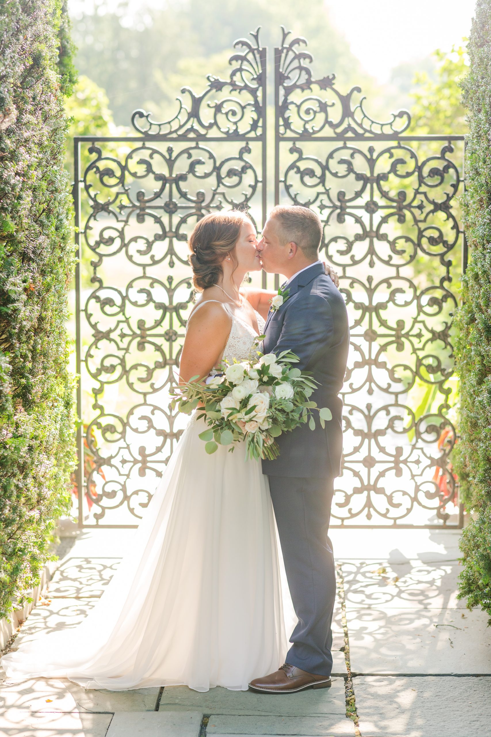 newlyweds kiss by iron fence at Drumore Estate
