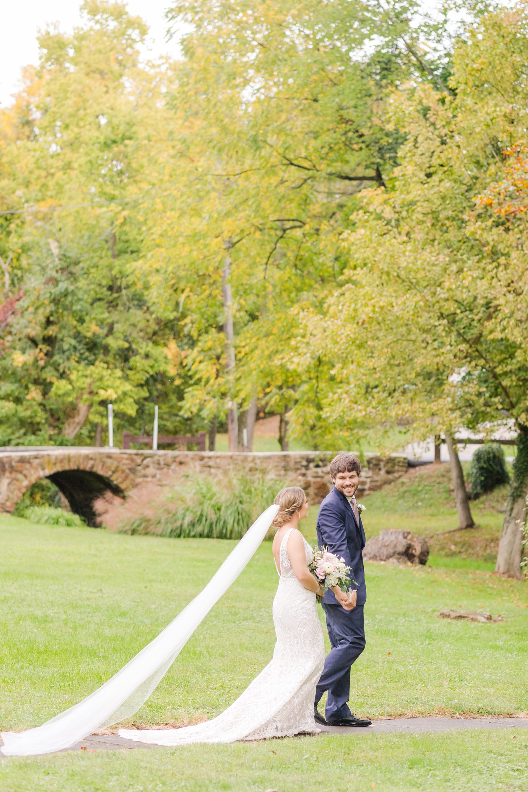 newlyweds walk near brick bridge at Historic Shady Lane