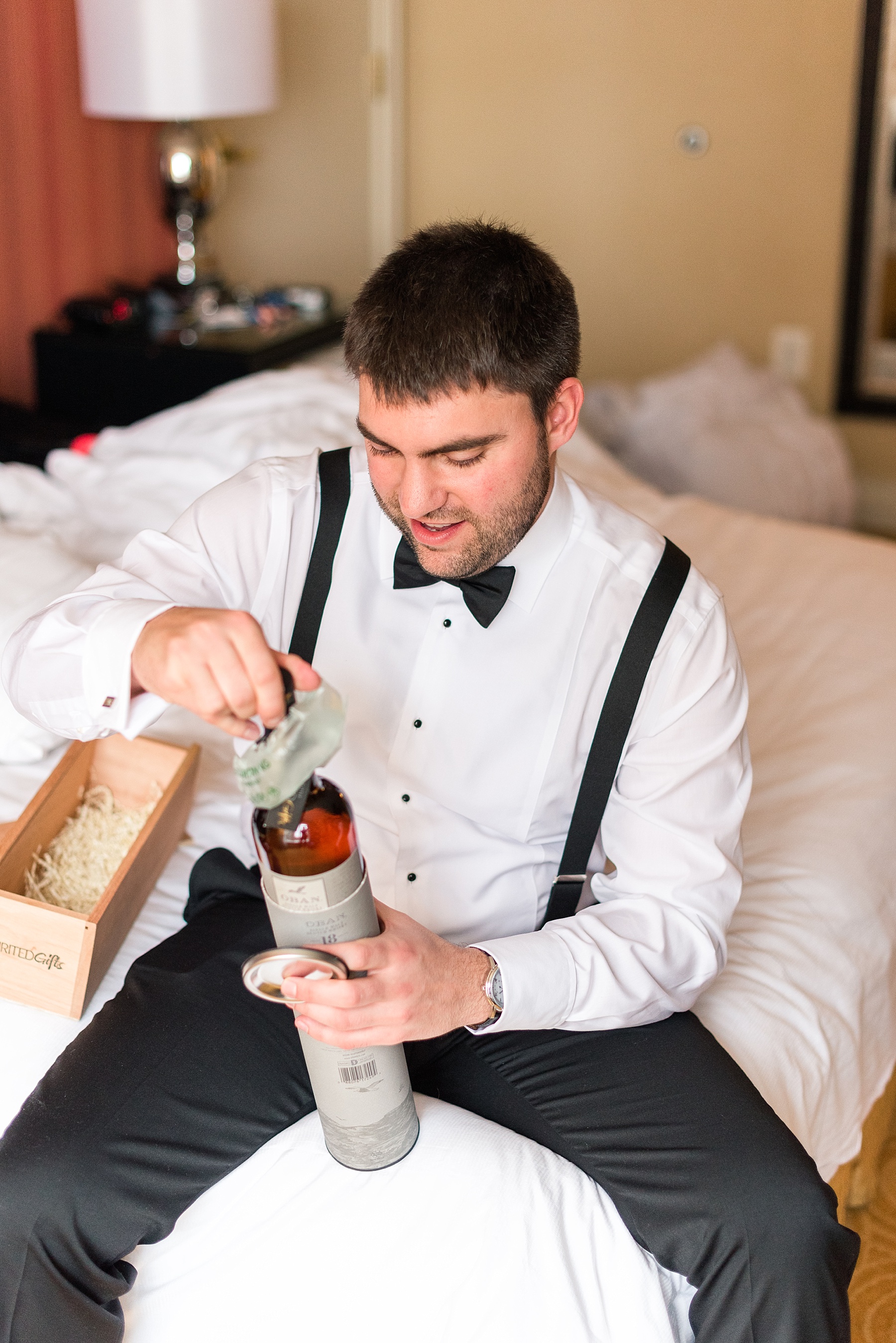 groom opens bottle of whiskey photographed by Alexandra Mandato Photography
