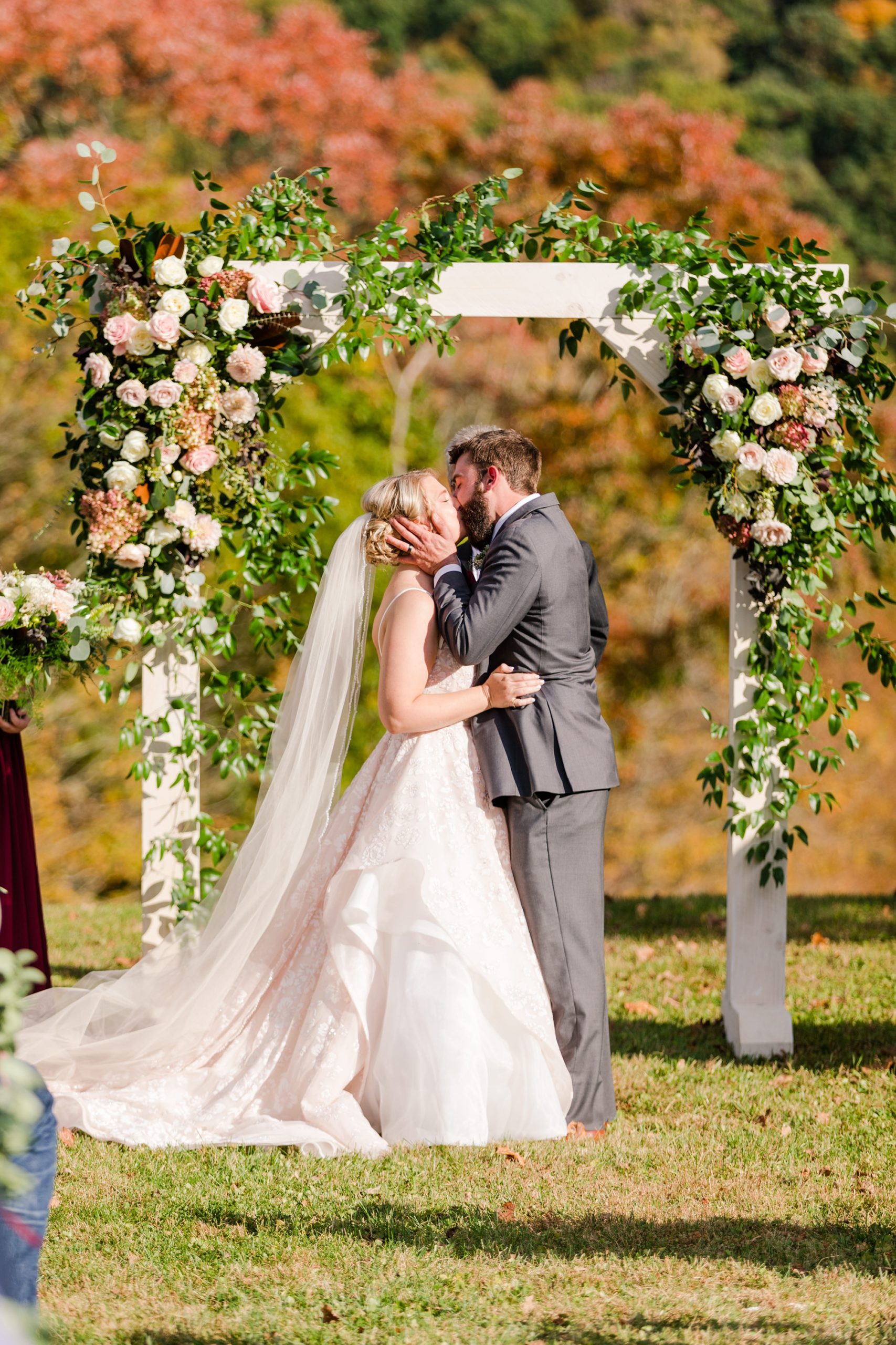 newlyweds kiss under floral arbor at Iron Works House