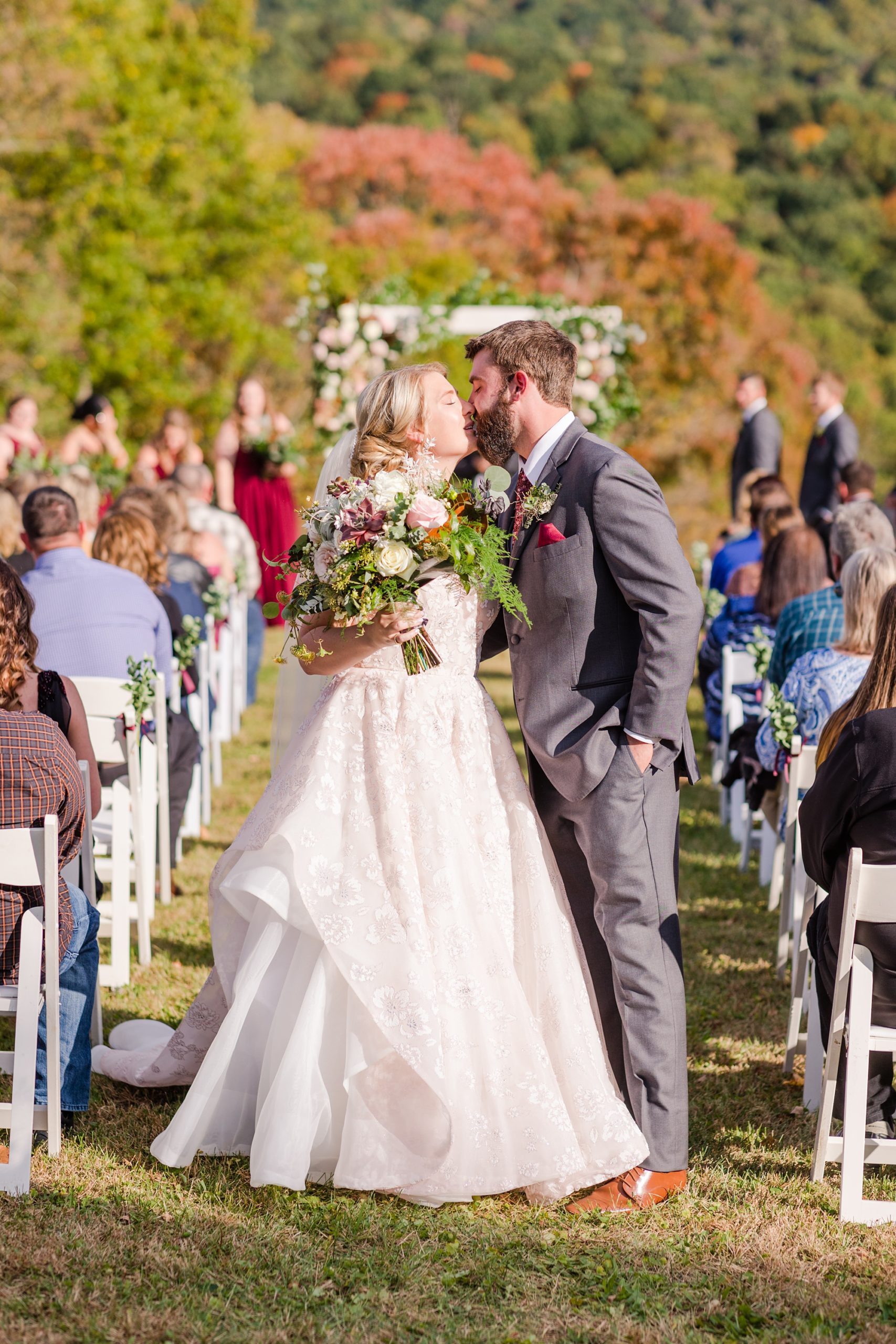 bride and groom kiss at end of aisle after fall wedding ceremony