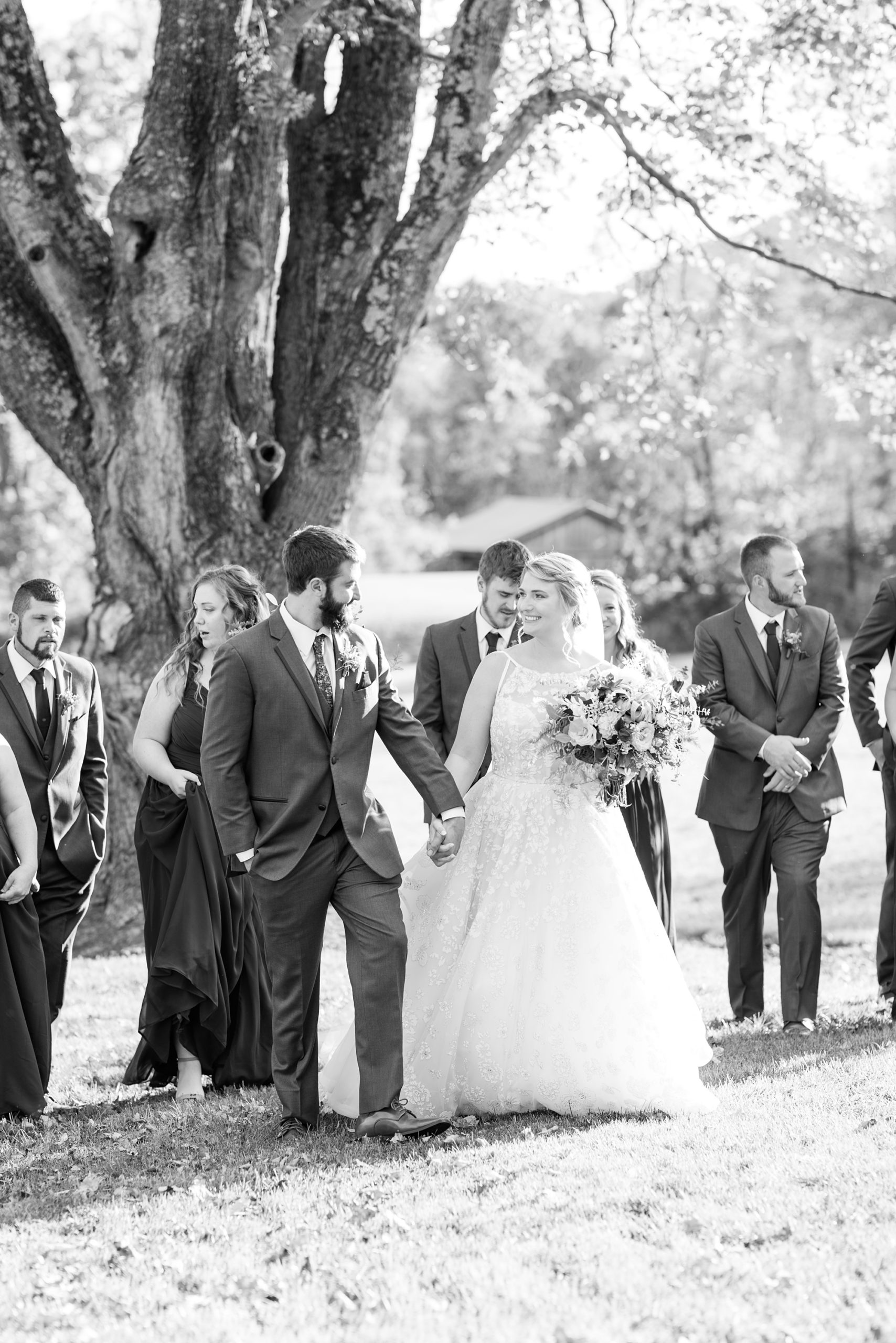 bride and groom walk with wedding party outside Iron Works House