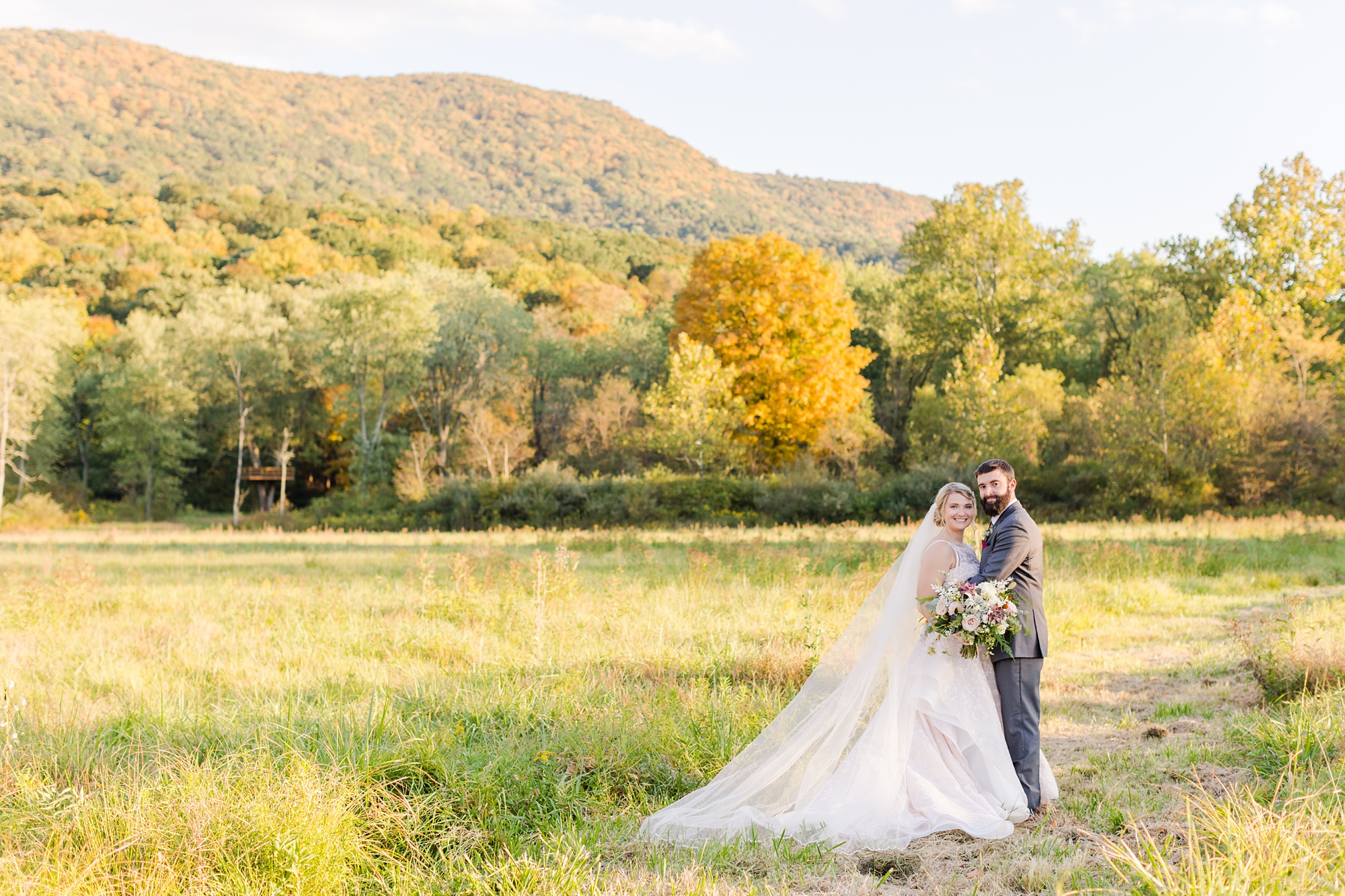 fall wedding portraits in front of orange and green trees