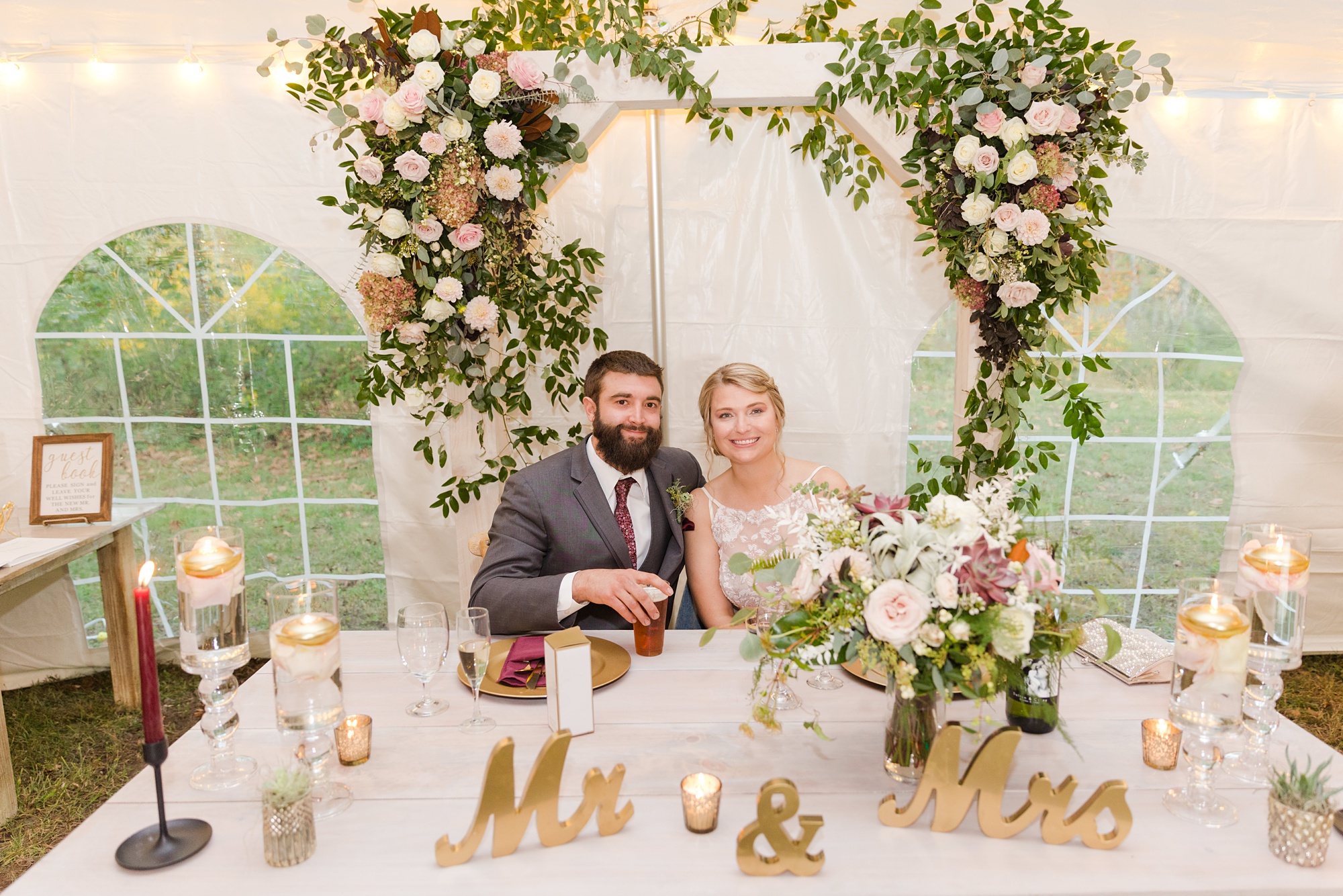 newlyweds sit at sweetheart table during Iron Works House wedding reception